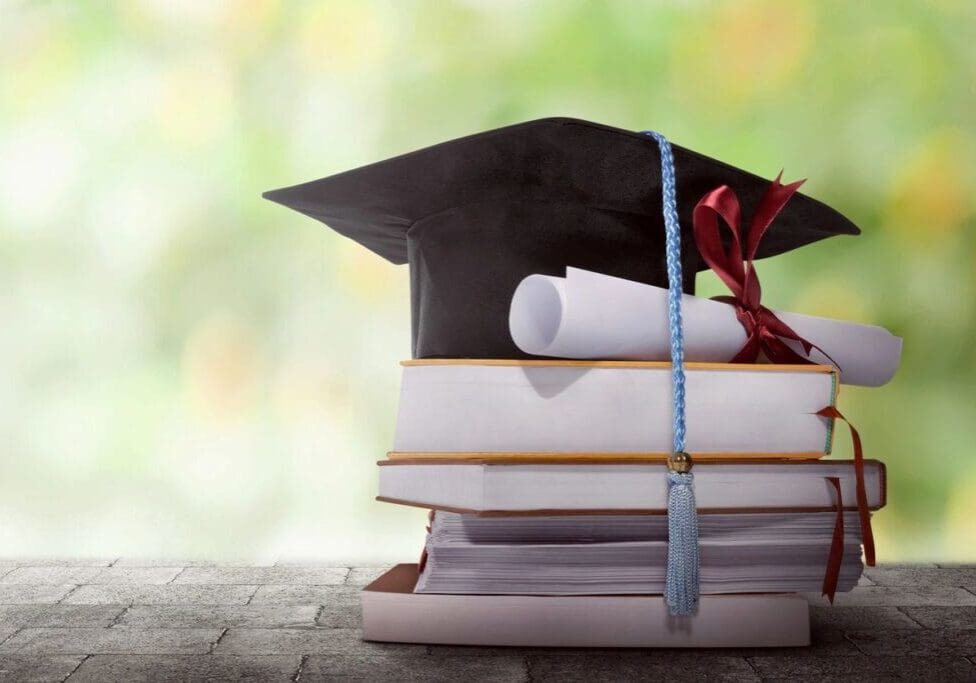 A stack of books with a graduation cap on top.